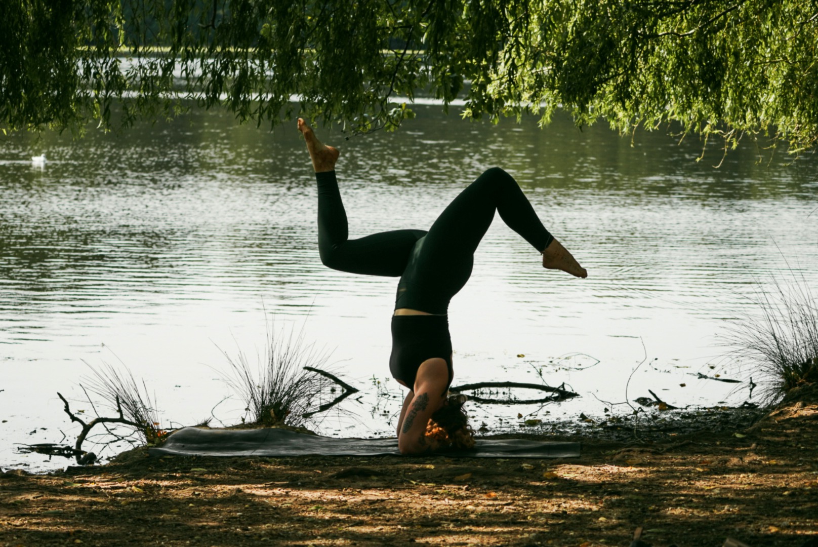 Grace in a headstand on a mat by the lake